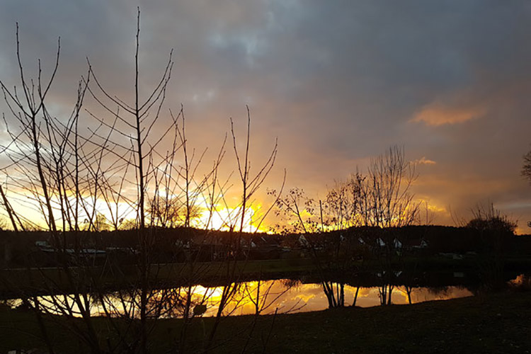 Sonnenuntergang über einem See in der Natur als Symbolbild für die Wintersonnwende.